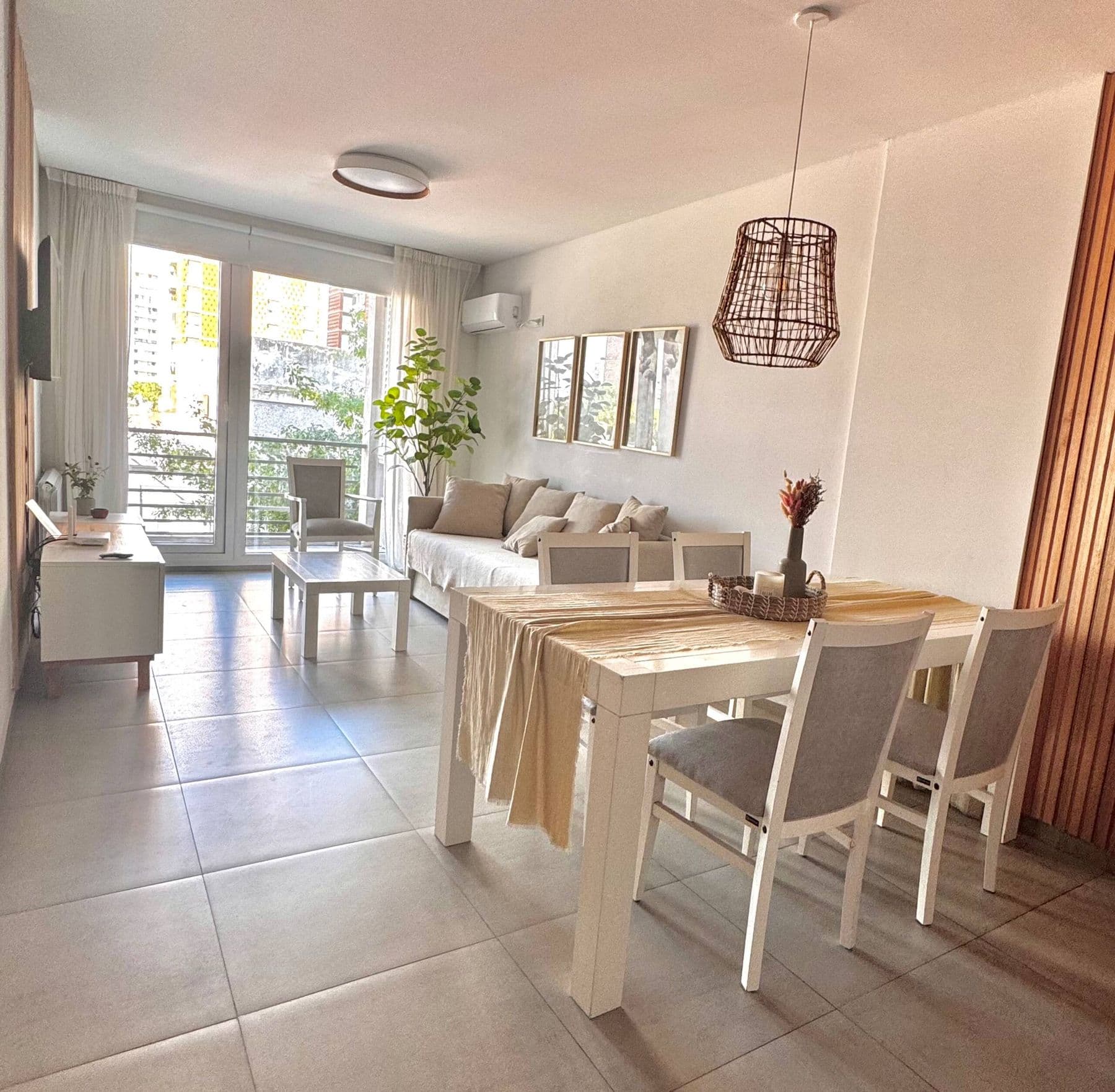 Living-comedor de Palazzo Tiberio 2 con mesa de madera, sillas blancas y lámpara de mimbre
