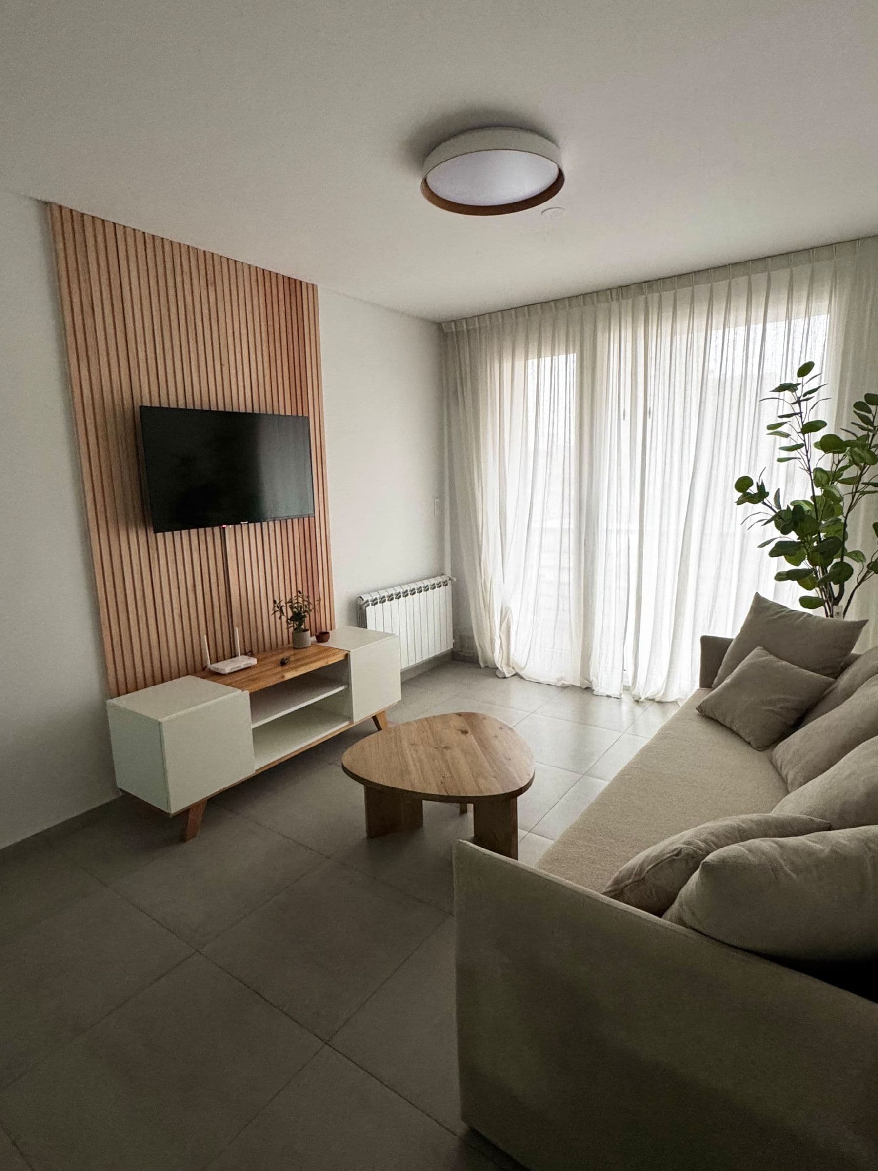 Living de Palazzo Tiberio 2 con panel de listones de madera, sillón de lino y televisor