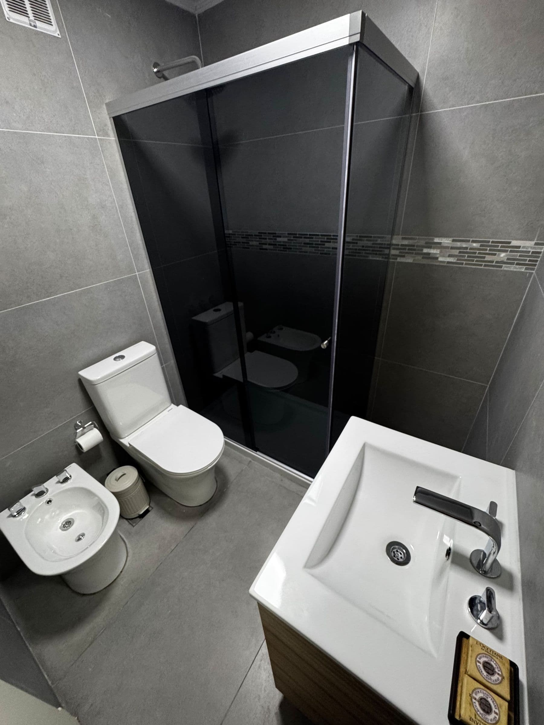 Baño con ducha de vidrio negro y mueble blanco