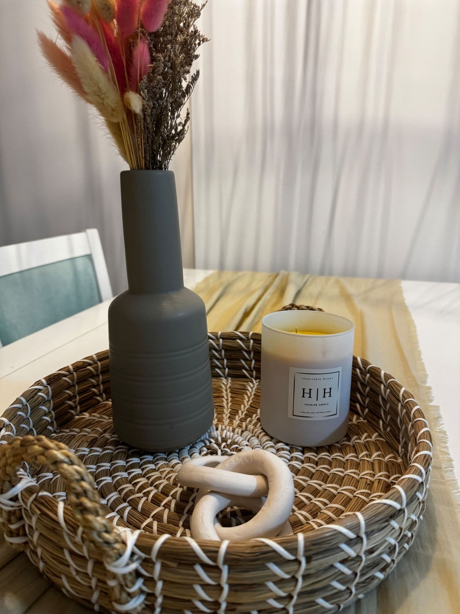 Canasto de mimbre con vela y flores secas sobre la mesa