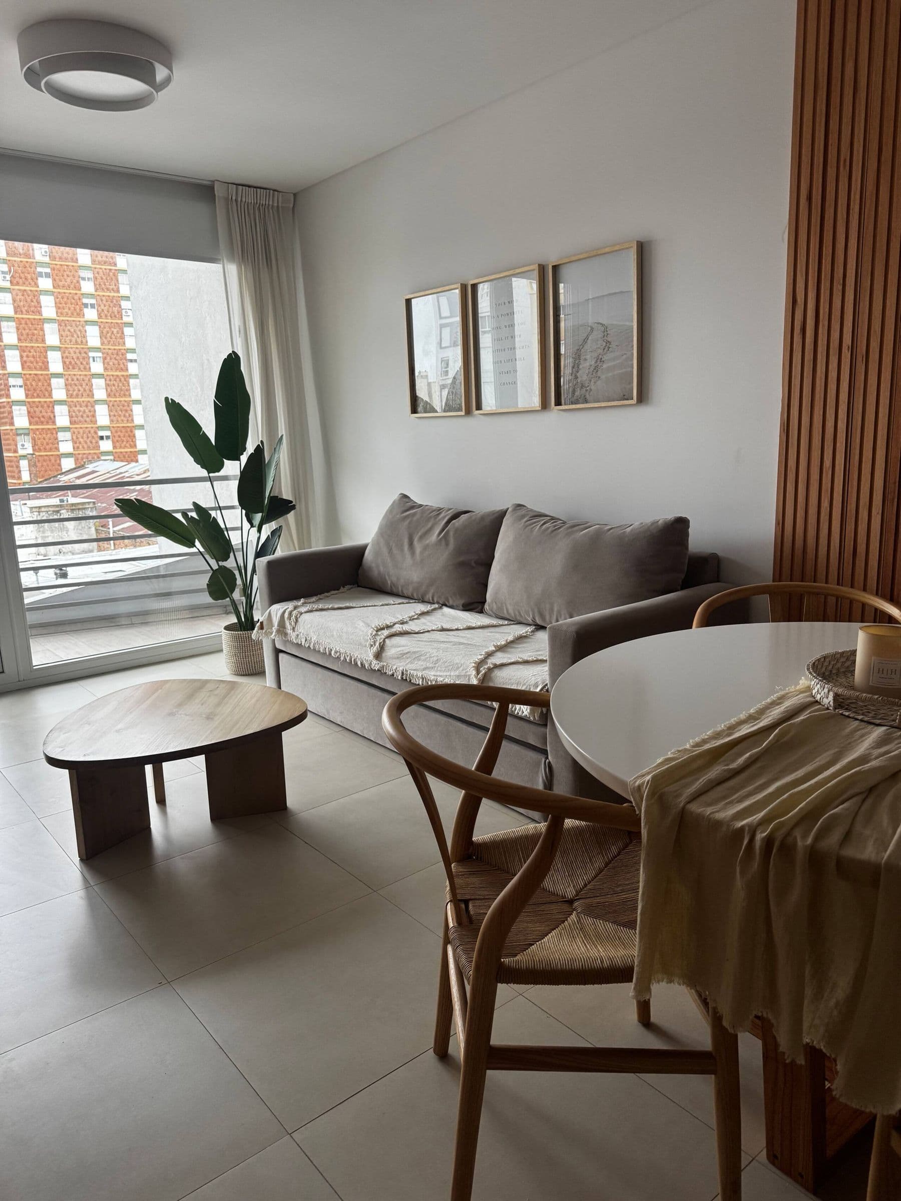 Living con sofá cama, mesa ratona de madera y luz natural