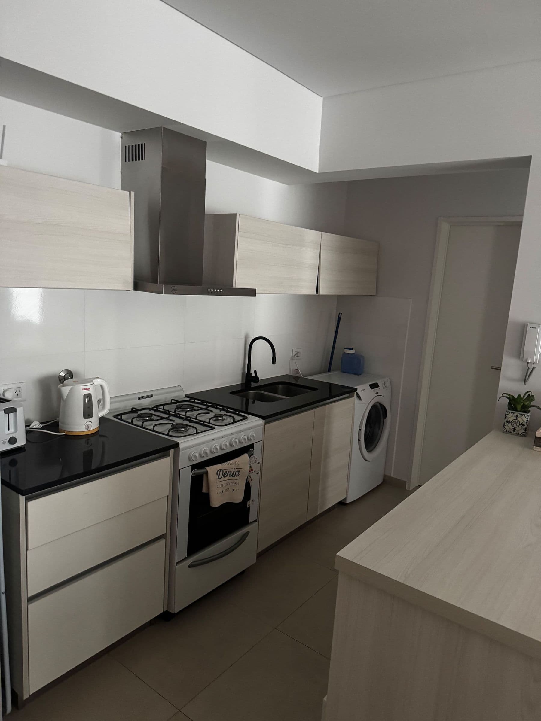 Cocina con anafe, horno, pava eléctrica y lavarropas
