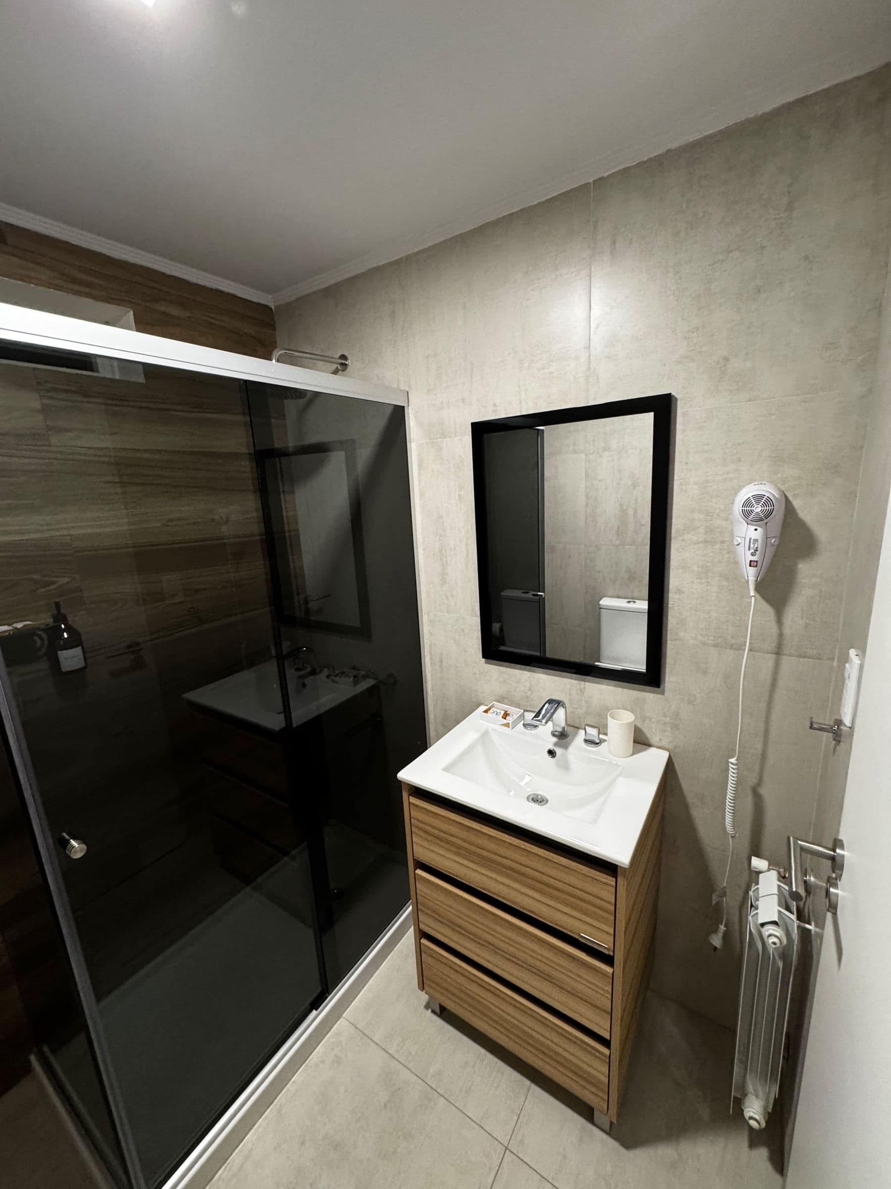 Baño con ducha de vidrio, espejo y mueble de madera
