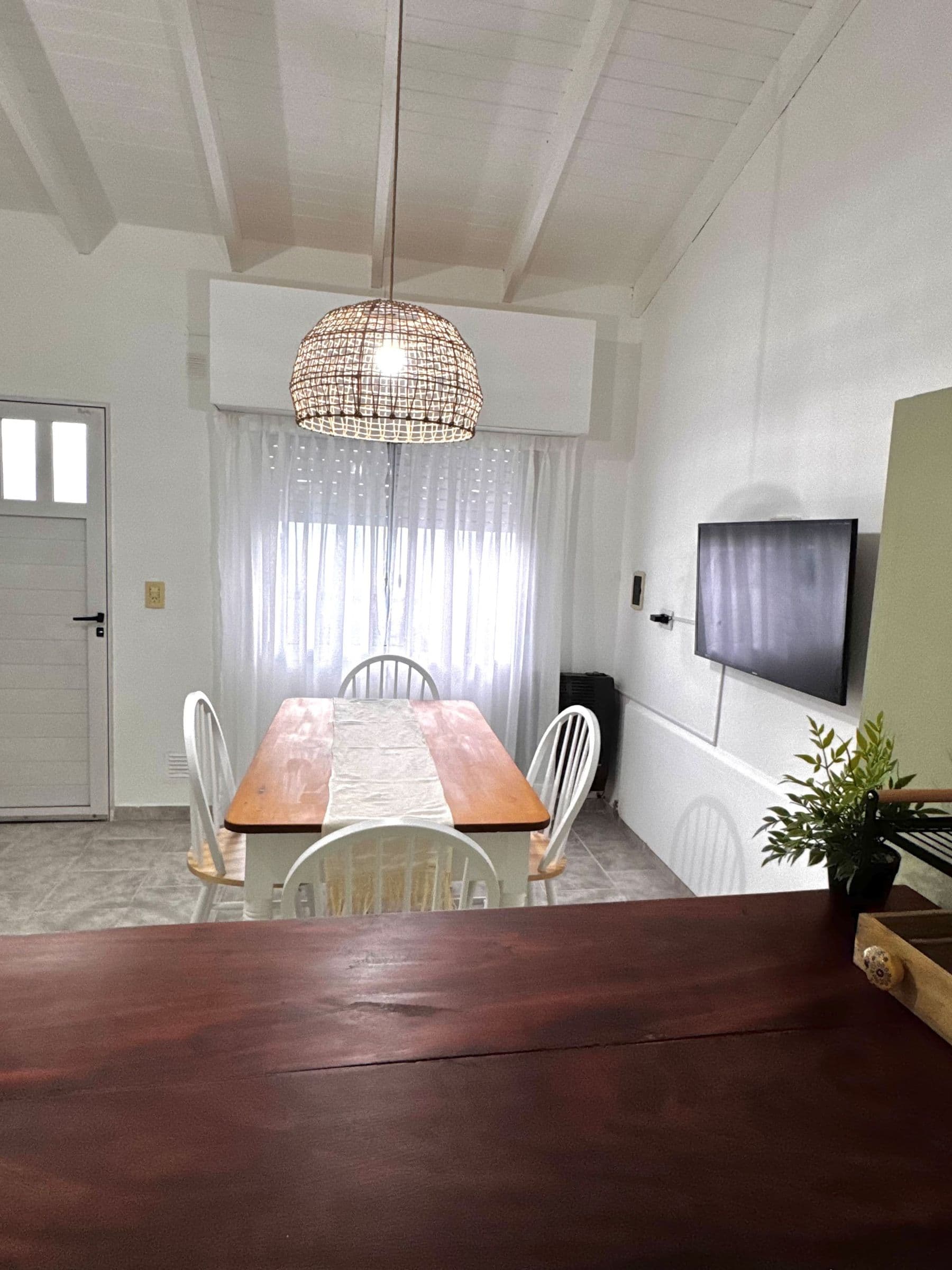 Comedor de Río Colorado con mesa de madera, sillas blancas y lámpara de mimbre