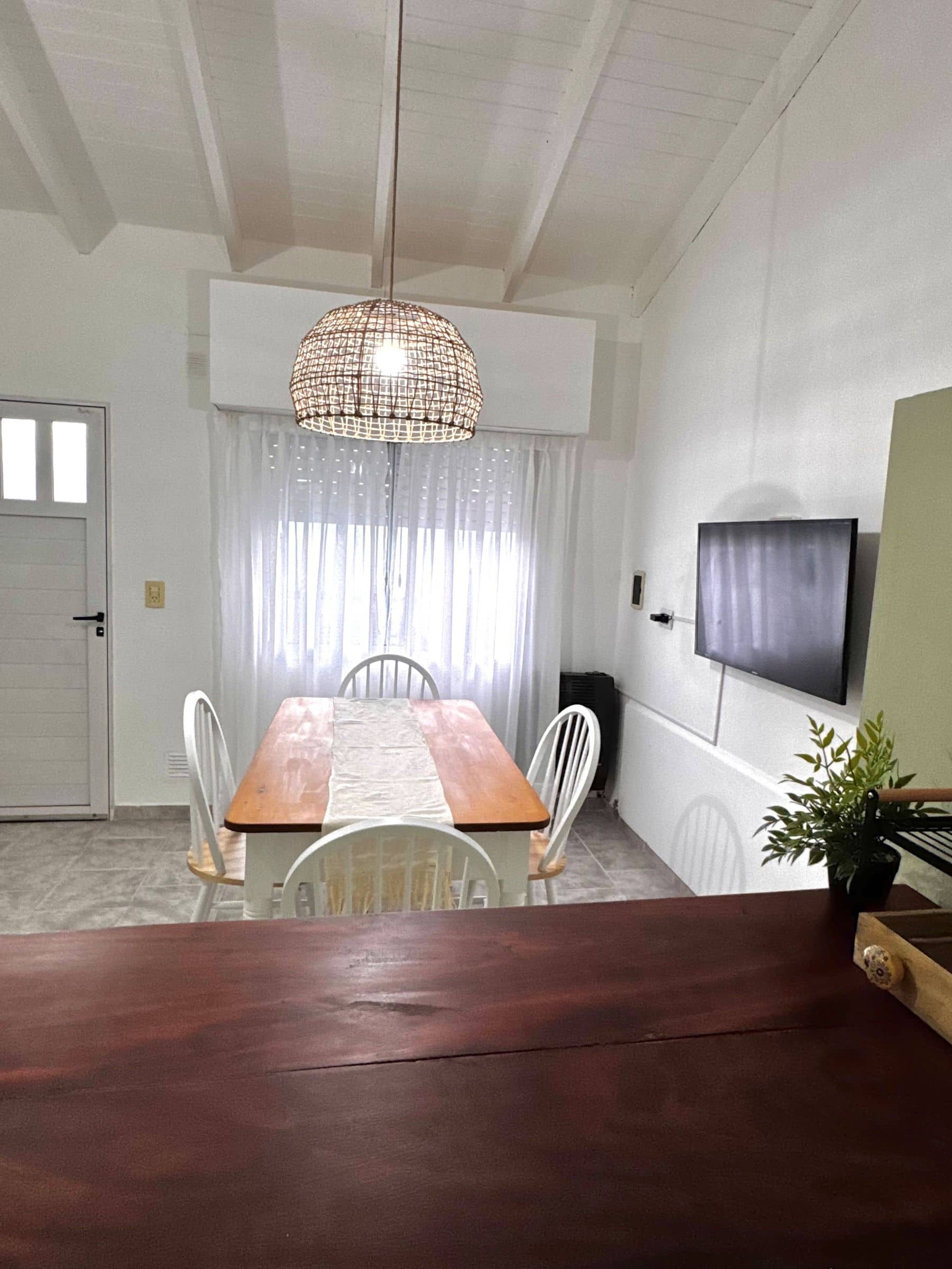 Comedor de Río Colorado con mesa de madera, sillas blancas y lámpara de mimbre